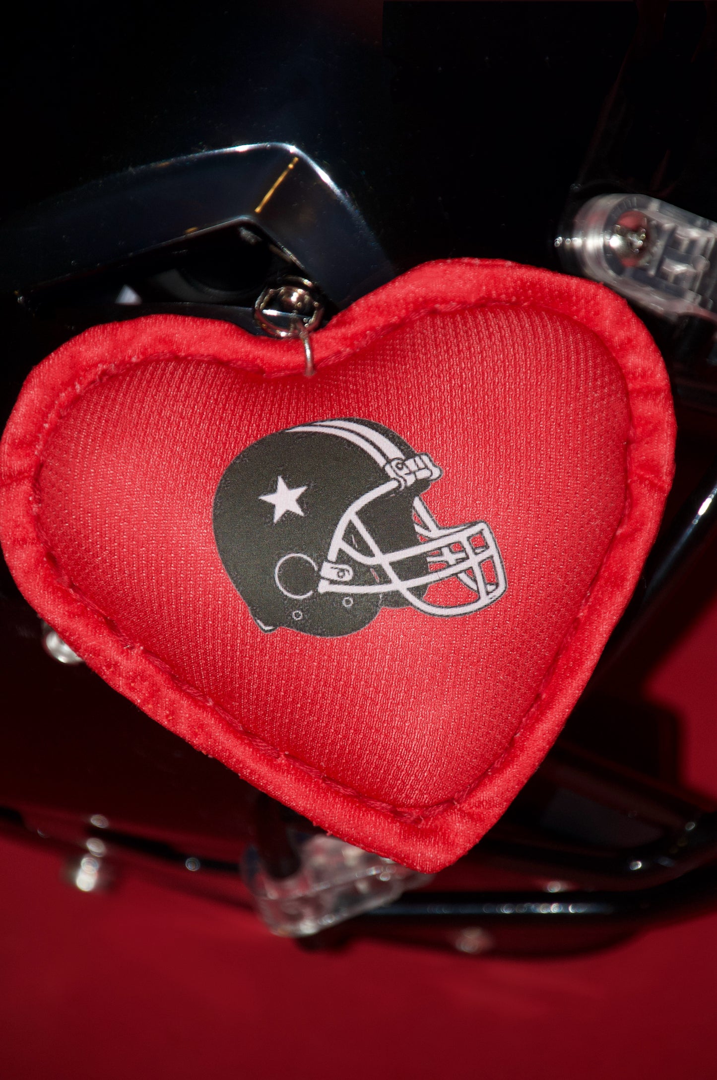 Red heart-shaped keychain with a helmet logo on a helmet