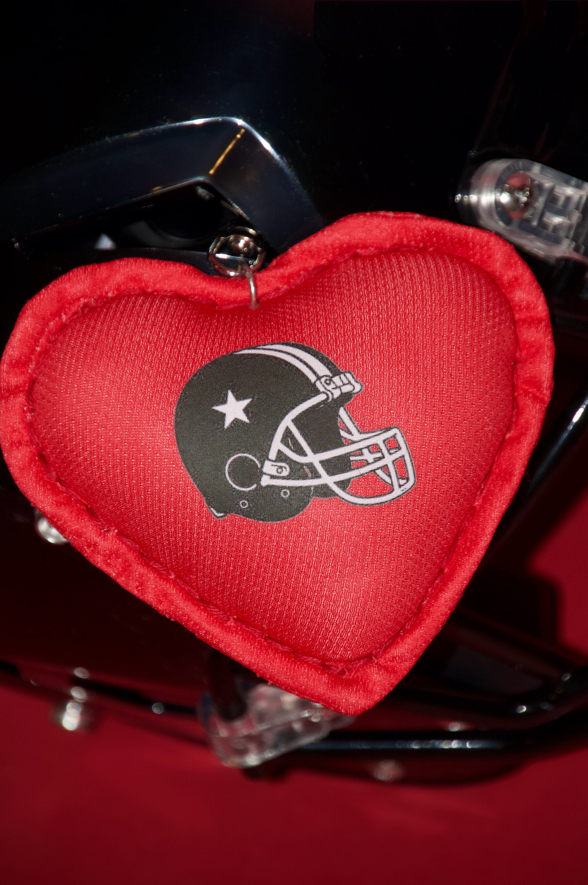 Red heart-shaped keychain with a helmet logo on a helmet